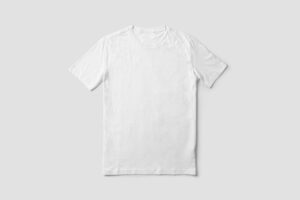 Person holding up two folded t-shirts, inspecting fabric weight and stitching under natural indoor light